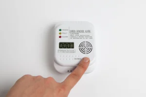person pressing test button on carbon monoxide detector after beeping alert