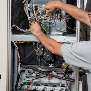 HVAC technician performing a heating system maintenance inspection inside a furnace cabinet