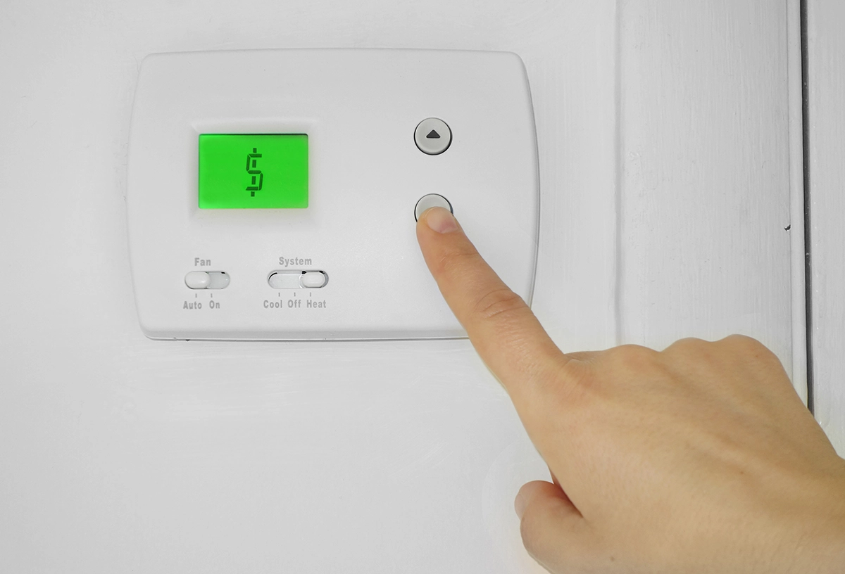 Thermostat displaying a dollar sign, highlighting why an electric bill may be so high during winter heating use